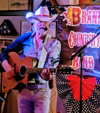 a man in a cowboy hat playing an acoustic guitar