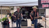 two men in cowboy hats standing in front of a tent